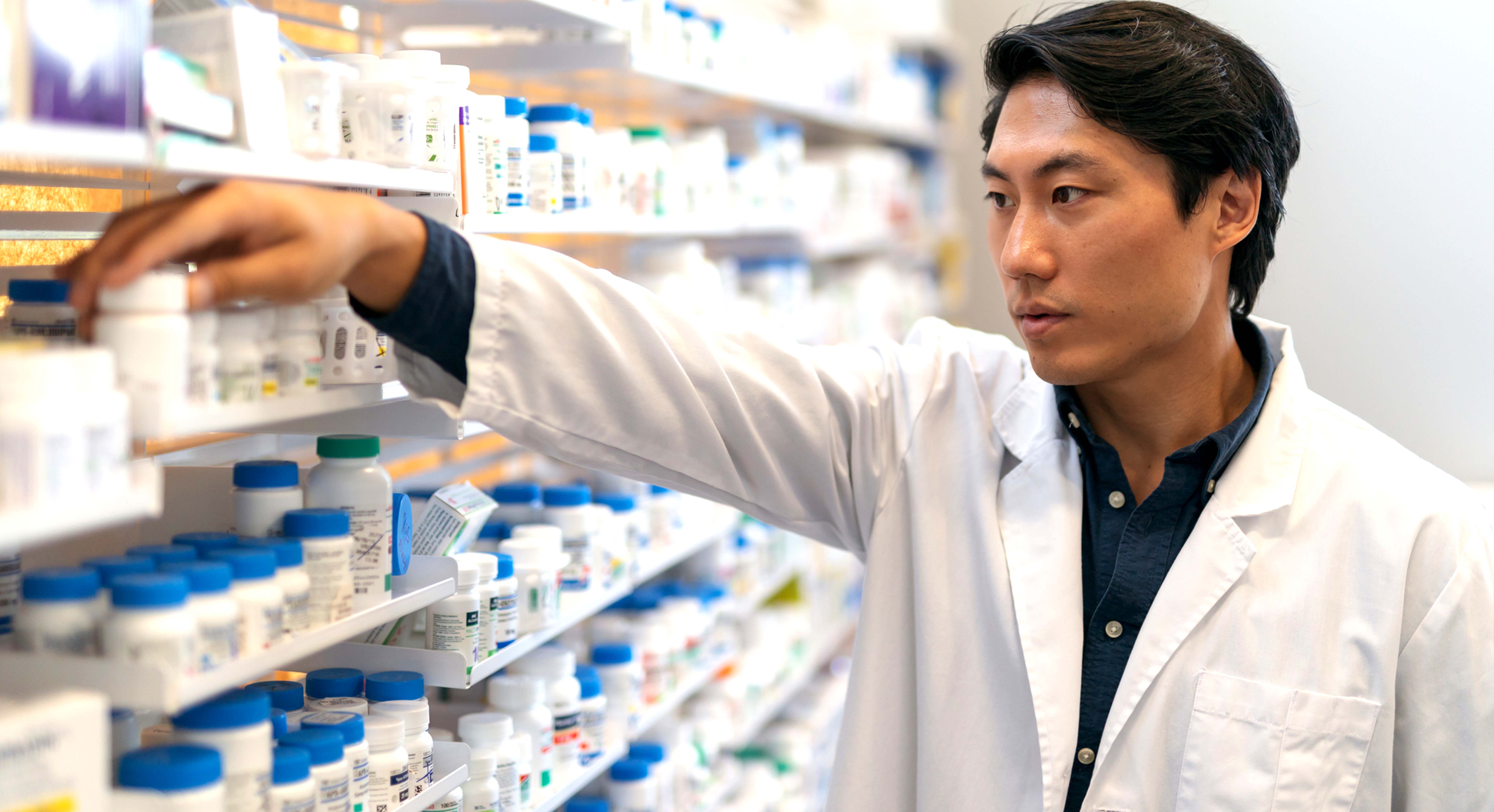 Pharmacist organizing pills on shelf