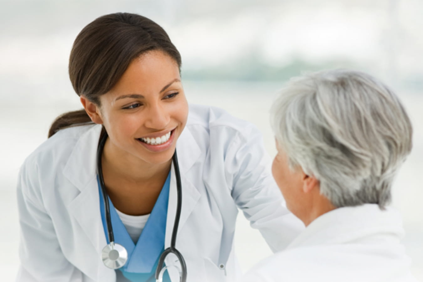 Infirmière souriant à une patiente senior assise